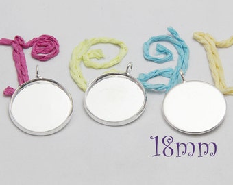 May include: Three silver-toned metal pendant trays with a round shape and a loop at the top. The trays are 18 mm in diameter and are perfect for adding a personal touch to jewelry projects.