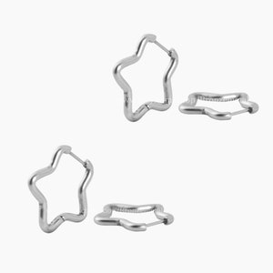 May include: A pair of silver star-shaped hoop earrings. The earrings are made of metal and have a simple, modern design.
