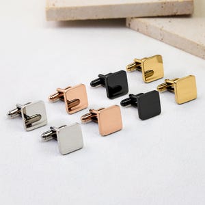 May include: A collection of square cufflinks in various metallic finishes, including silver, rose gold, black, and gold. Each cufflink features a smooth, polished surface and a standard swivel-style toggle mechanism for securing to a shirt cuff.