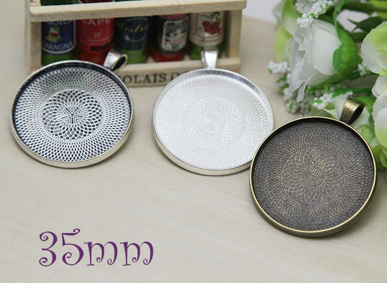May include: Three round pendant trays in silver, bronze, and a plain silver finish. The silver tray has a detailed openwork design. The bronze tray has a detailed circular pattern. The text "35mm" is visible in the image, indicating the size of the trays.