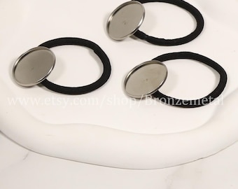 May include: Three black elastic hair ties with silver metal round embellishments. The hair ties are on a white surface.