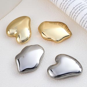May include: Four compact mirrors with irregular, organic shapes. Two mirrors feature a polished gold-tone finish, while the other two have a reflective silver-tone finish. Each mirror has a smooth, rounded surface with a high-gloss, metallic appearance.