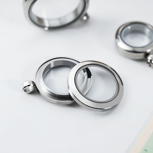 May include: Two silver locket pendants with clear glass inserts. The locket pendants are open and ready to be filled with a small photo or other memento.