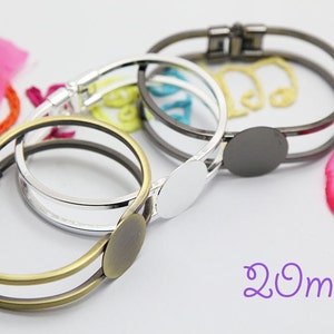 May include: Three metal bangle bracelets with a 20mm round blank for customization. The bracelets are in silver, gold, and black.