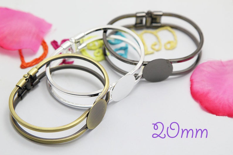 May include: Three metal bangle bracelets with a 20mm round blank for customization. The bracelets are in silver, gold, and black.