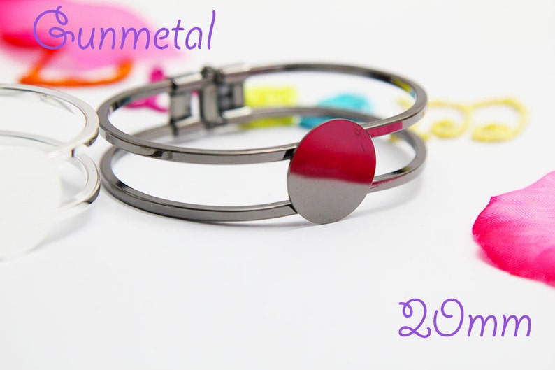 May include: Gunmetal bracelet with a 20mm round bezel for adding a charm or embellishment. The bracelet is double-layered and has a hinged clasp.