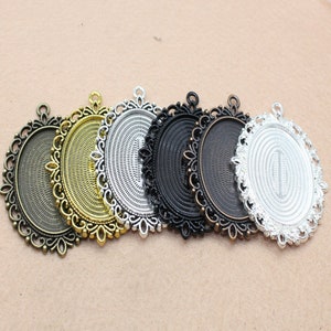 May include: Six oval-shaped metal pendant trays with ornate filigree edges. The trays are in various finishes, including gold, silver, and black.