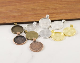 May include: A collection of round pendant trays in various metallic finishes, including bronze, copper, silver, and gold. Each tray has a loop for attaching a chain or cord. The trays are empty, ready for custom designs or inserts.