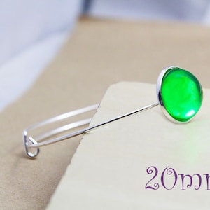 May include: A silver bangle bracelet with a green glass cabochon. The cabochon is 20mm in diameter.