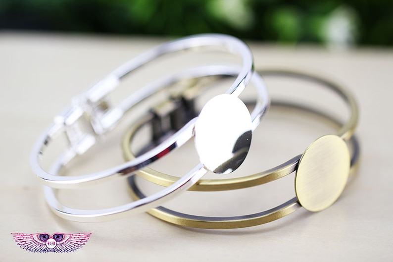 May include: Two silver and one gold bangle bracelets with round, blank, metal charms. The charms are smooth and have a shiny finish.