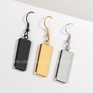 Op de afbeelding: Drie rechthoekige oorhangers in zwart, goud en zilver. Elke oorbel heeft een haak en een rechthoekige hanger. Het websiteadres "www.etsy.com/shop/Bronzemetal" staat onderaan de afbeelding.