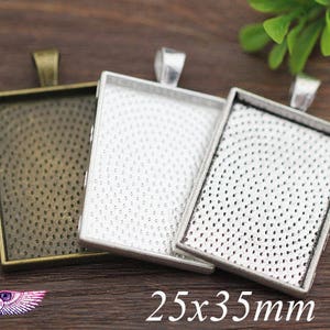 Może przedstawiać: Trzy srebrne i brązowe tace do zawieszek z fakturowaną powierzchnią. Tace są prostokątne i mają wymiary 25 x 35 mm.