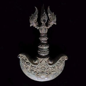 May include: A bronze-colored ritual knife with a curved blade and ornate handle. The handle features a detailed, three-pronged design at the top and intricate carvings throughout. The blade has a curved shape with decorative patterns.