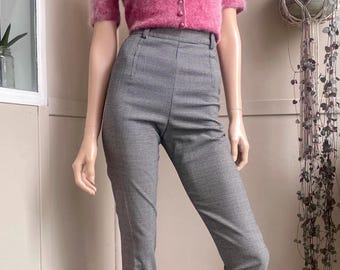May include: A short-sleeved, fuzzy pink cardigan with a high collar and a row of matching buttons, paired with high-waisted, slim-fit trousers featuring a small-scale black and white houndstooth pattern that extends to the mid-calf length.