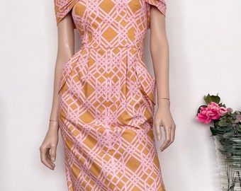 May include: A pink and yellow off-the-shoulder dress with a geometric pattern. The dress has a fitted bodice and a slightly flared skirt.