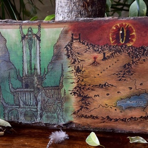 May include: A hand-painted wooden artwork depicting a fantasy map with two distinct scenes. One side features a tall, dark tower against a green backdrop, while the other shows a fiery landscape with a large eye. The artwork is mounted on a piece of natural wood.