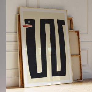 May include: A framed print of a black and white abstract design featuring a snake with a red mouth. The print is on a cream background and has a gold frame.