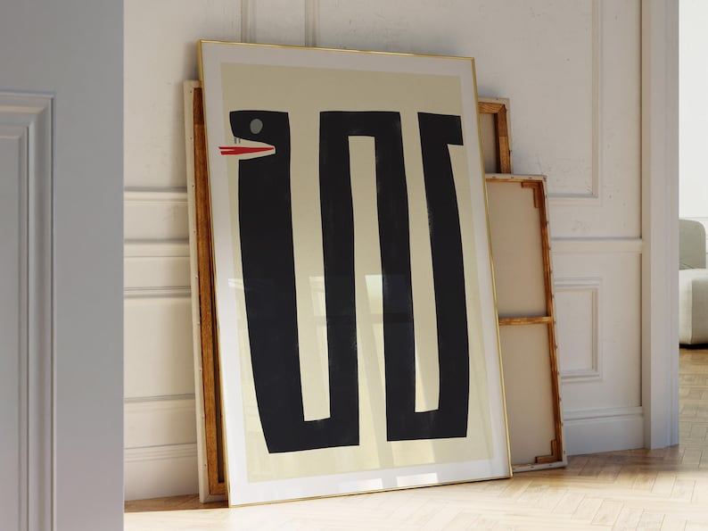 May include: A framed print of a black and white abstract design featuring a snake with a red mouth. The print is on a cream background and has a gold frame.
