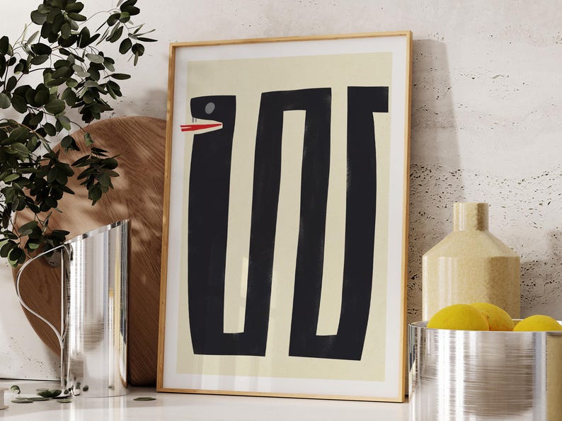 May include: A framed abstract print with a black and white design of a snake with a red mouth on a cream background.