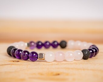 May include: A purple amethyst, pink rose quartz, and black lava rock beaded bracelet with a silver spacer bead.
