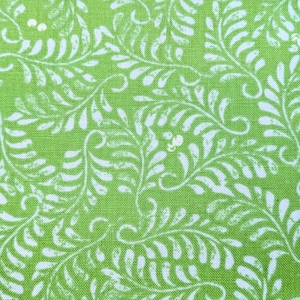 May include: Green fabric with a white floral pattern. The pattern features stylized leaves and branches.