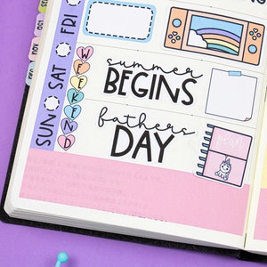 Op de afbeelding: Een roze en gele planner met kleurrijke stickers. De stickers bevatten harten, een regenboog, een videogameconsole, een eenhoorn en tekst die "Summer Begins", "Father's Day", "Grocery Shopping" en "Weekend" zegt.