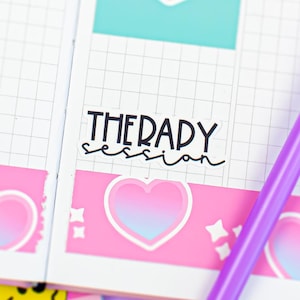 May include: A white grid-patterned planner page featuring a sticker with the text "THERAPY session" in black, a heart-shaped sticker with the text "Resist!", and a pink border with heart icons. A purple pen with a fuzzy topper lies across the page.