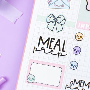 Może przedstawiać: Strona planera w kolorze różowym i białym z siatką. Na stronie znajdują się naklejki z napisami "Meal Prep", "Memory Plan" i "Important". Są też naklejki z czaszkami i kokardką.
