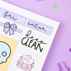 Puede incluir: Un planificador semanal con pegatinas para cada día de la semana. Las pegatinas incluyen una calavera, un lazo, un sobre con un corazón y las palabras "factura vencida", y las palabras "limpieza profunda".