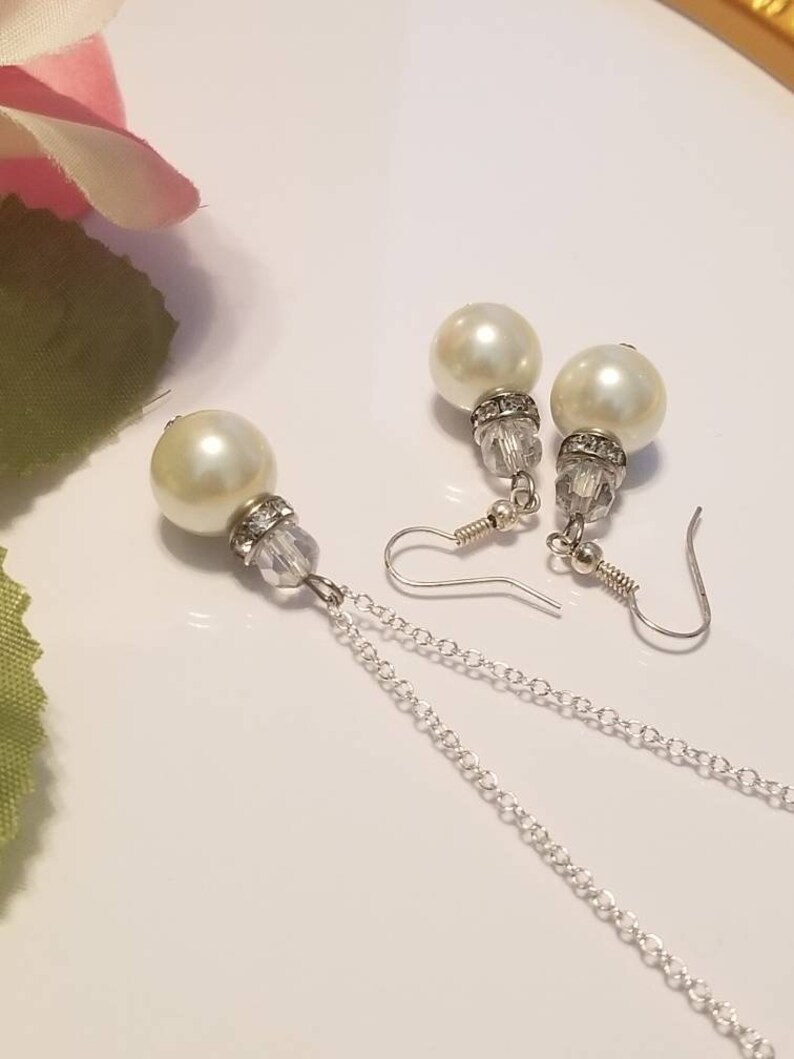 May include: A set of pearl earrings and a pearl necklace with a silver chain. The earrings feature a crystal bead and a pearl drop. The necklace has a single pearl drop and a silver chain.