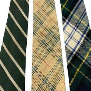 Pode incluir: Tr&ecirc;s gravatas com padr&otilde;es diferentes. Uma &eacute; verde com listras brancas, outra &eacute; bege com xadrez vermelho e azul, e a &uacute;ltima &eacute; xadrez verde, azul e branco.