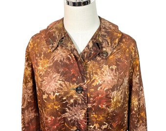 Puede incluir: Una chaqueta de color marrón y dorado con estampado, cuello y cierre de botones. La chaqueta tiene un corte holgado y está hecha de una tela suave y ligera.