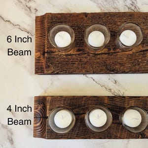 May include: Two rustic wooden candle holders, one 6 inches wide and the other 4 inches wide, each with three clear glass votive holders. Each votive holds a white candle. The wood has a natural, distressed finish.