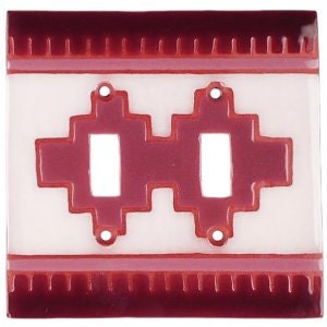 May include: A white ceramic double light switch cover with a red geometric design. The switch cover has two rectangular openings for the light switches.