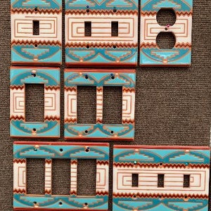 May include: Set of six ceramic light switch covers with a Southwestern design. The covers feature a turquoise and brown geometric pattern with white accents. The covers are in various sizes, including single, double, and triple switch covers.