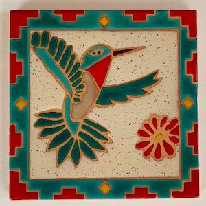 May include: A ceramic tile with a colorful hummingbird design. The hummingbird is green, blue, and red with a white background. The tile has a turquoise border with red and yellow accents.