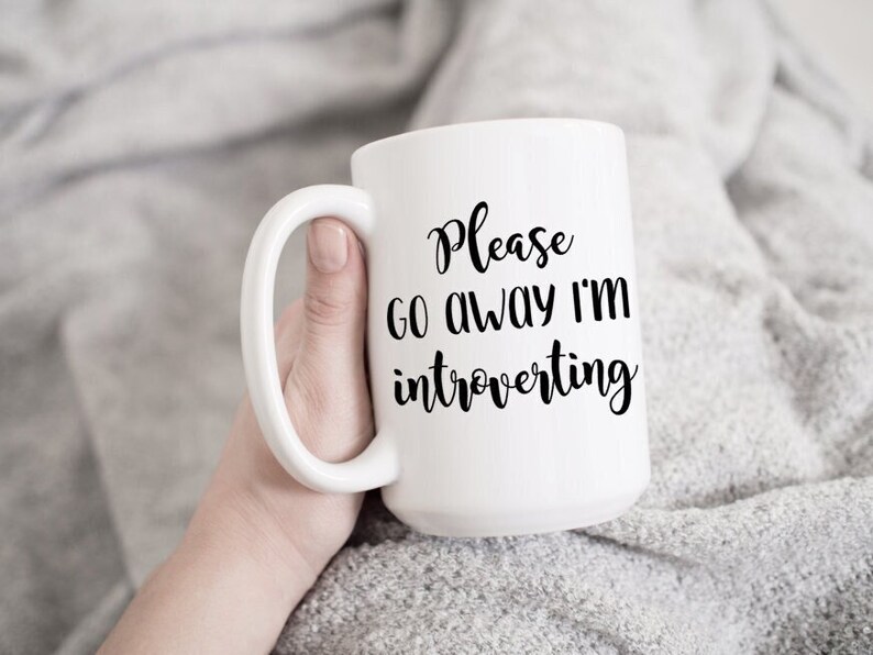 May include: White ceramic mug with black text that reads "Please go away I'm introverting".