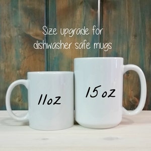 Op de afbeelding: Twee witte keramische mokken naast elkaar. De kleinere mok is gelabeld met 11oz en de grotere mok met 15oz. De tekst boven de mokken luidt Size upgrade for dishwasher safe mugs. De mokken hebben een gladde afwerking en een standaard handvat.