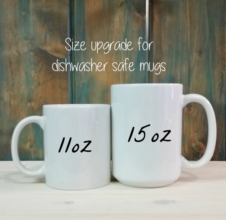 Op de afbeelding: Twee witte keramische mokken naast elkaar. De kleinere mok is gelabeld met 11oz en de grotere mok met 15oz. De tekst boven de mokken luidt Size upgrade for dishwasher safe mugs. De mokken hebben een gladde afwerking en een standaard handvat.