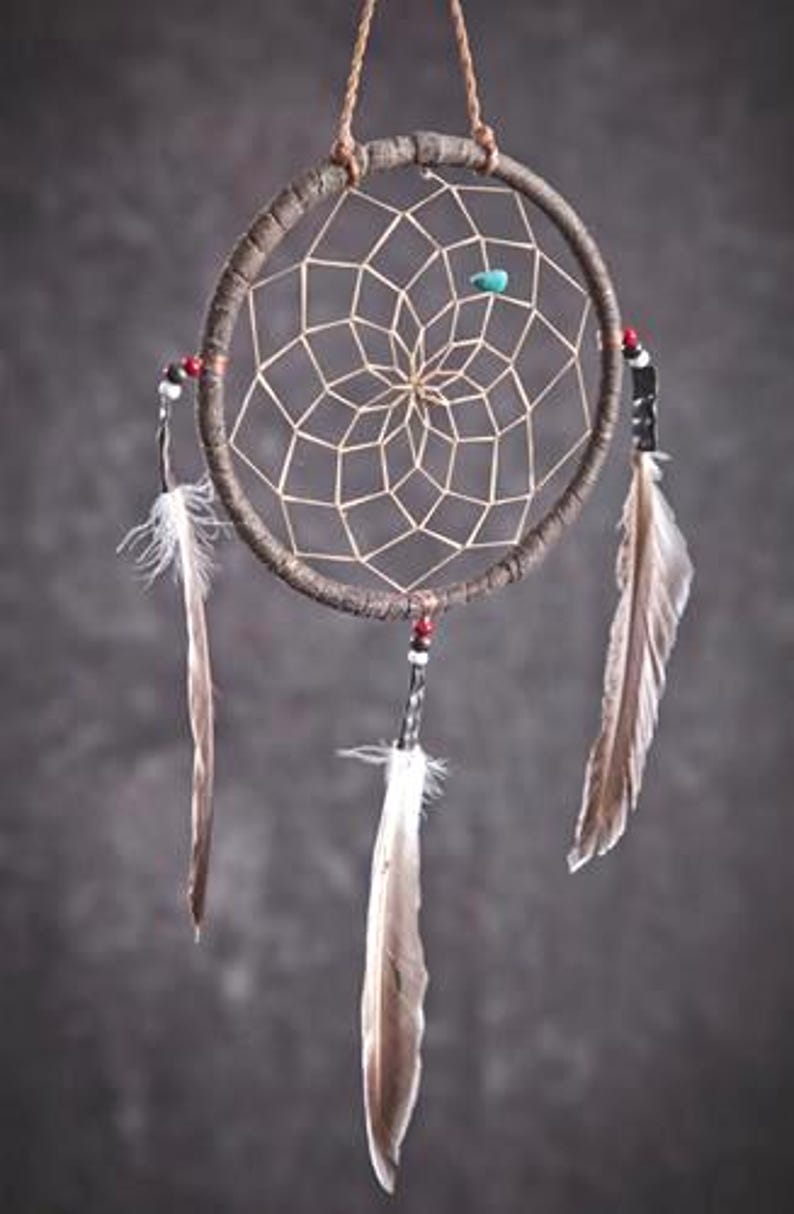 May include: A brown dreamcatcher with white feathers and beads hanging from it. The dreamcatcher has a circular frame with a web-like pattern in the center.