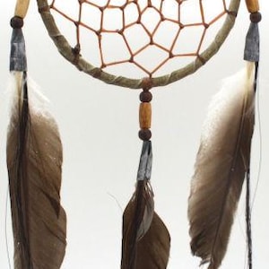 May include: A brown dream catcher with a woven web and feathers hanging from the bottom. The dream catcher has a wooden ring and brown beads.