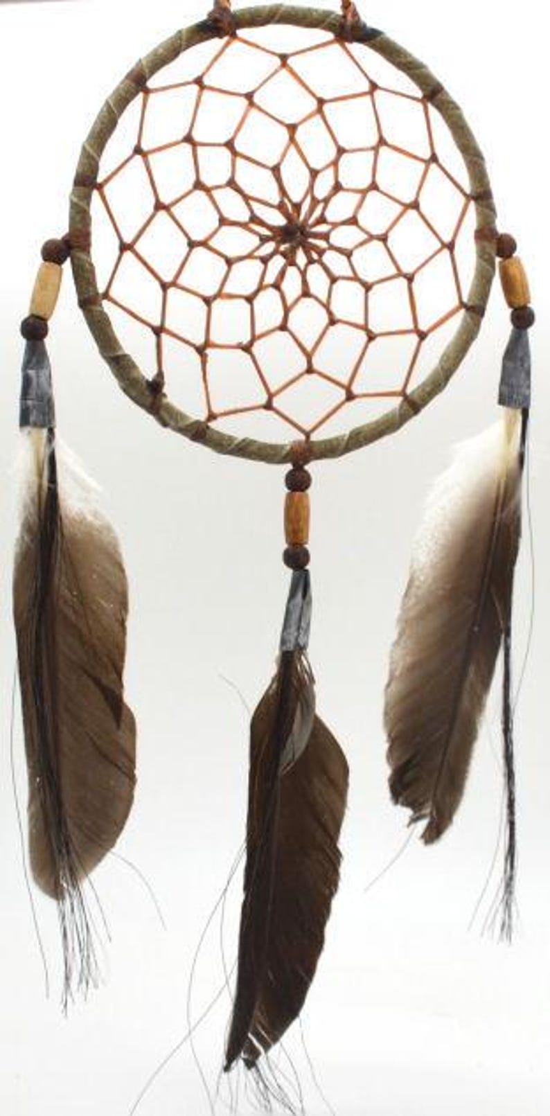 May include: A brown dream catcher with a woven web and feathers hanging from the bottom. The dream catcher has a wooden ring and brown beads.