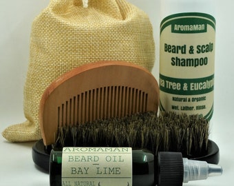 May include: A beard care set with a brown burlap bag, a wooden comb, a boar bristle brush, a bottle of beard oil labeled "Aromaman Beard Oil Bay Lime All Natural Ingredients", and a bottle of shampoo labeled "Aromaman Beard & Scalp Shampoo Tea Tree & Eucalyptus Natural & Organic Wet. Lather. Rinse."