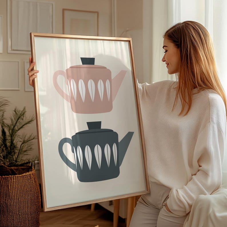 May include: A framed print with a minimalist design featuring two teapots. One teapot is pink with white accents and the other is dark gray with white accents.