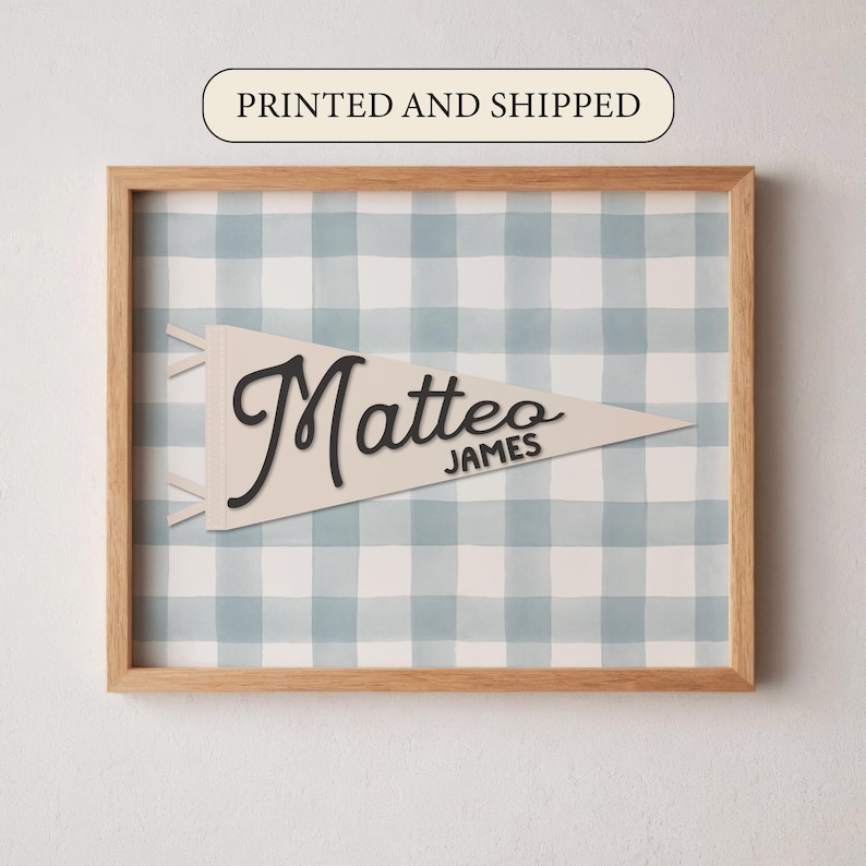 May include: A framed print featuring a light-colored pennant with the name "Matteo" in black script and the name "JAMES" below it. The background is a blue and white checkered pattern, all within a wooden frame. The text "PRINTED AND SHIPPED" is at the top.