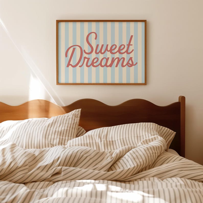May include: A bedroom scene featuring a wooden headboard and striped bedding. A framed print with the words "Sweet Dreams" in a cursive font hangs above the bed. The print has a light blue and cream striped background.