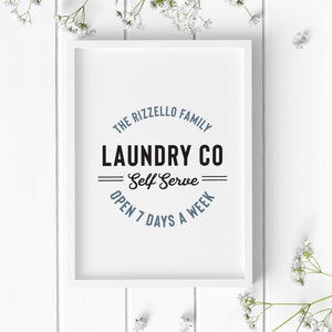 May include: White framed print with a blue and black logo that reads "The Rizzello Family Laundry Co. Self Serve Open 7 Days A Week"