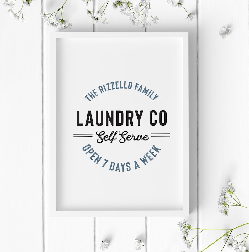 May include: White framed print with a blue and black logo that reads "The Rizzello Family Laundry Co. Self Serve Open 7 Days A Week"
