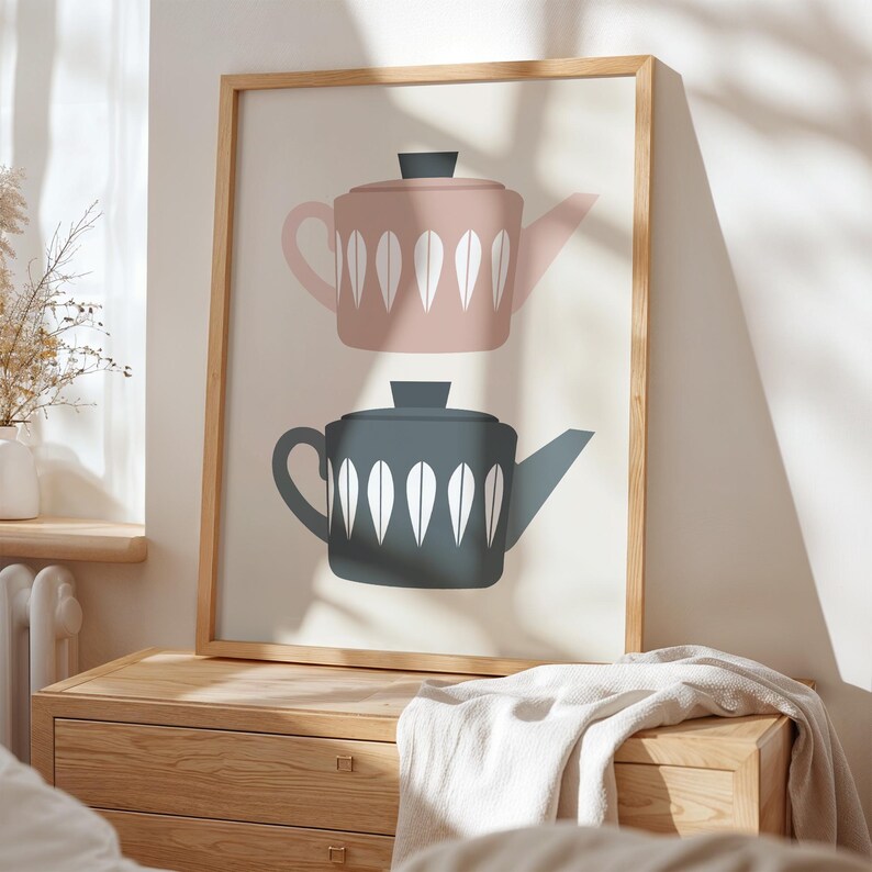 May include: A framed print with a minimalist design featuring two teapots. The top teapot is pink with white leaf-like patterns and the bottom teapot is gray with white leaf-like patterns.