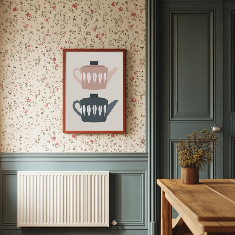May include: A framed print of two teapots, one pink and one blue, with white leaf designs against a beige background.